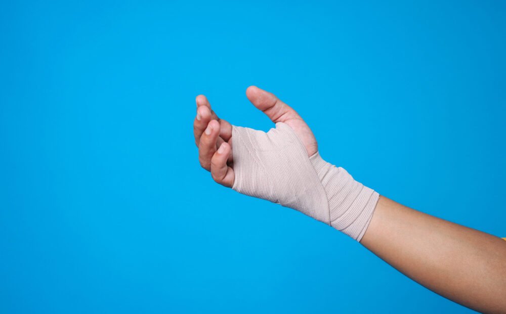 injured-broken-wrist-arm-with-elastic-bandage-isolated-blue-background-sprain-stress-fractu