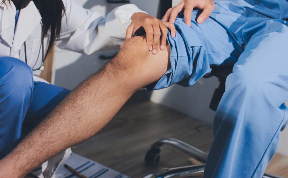 Physical therapist teaching a patient how to do exercises for his knee pain