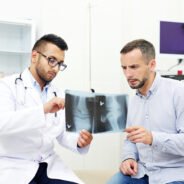 Radiologist and young man discussing x-ray images of joints